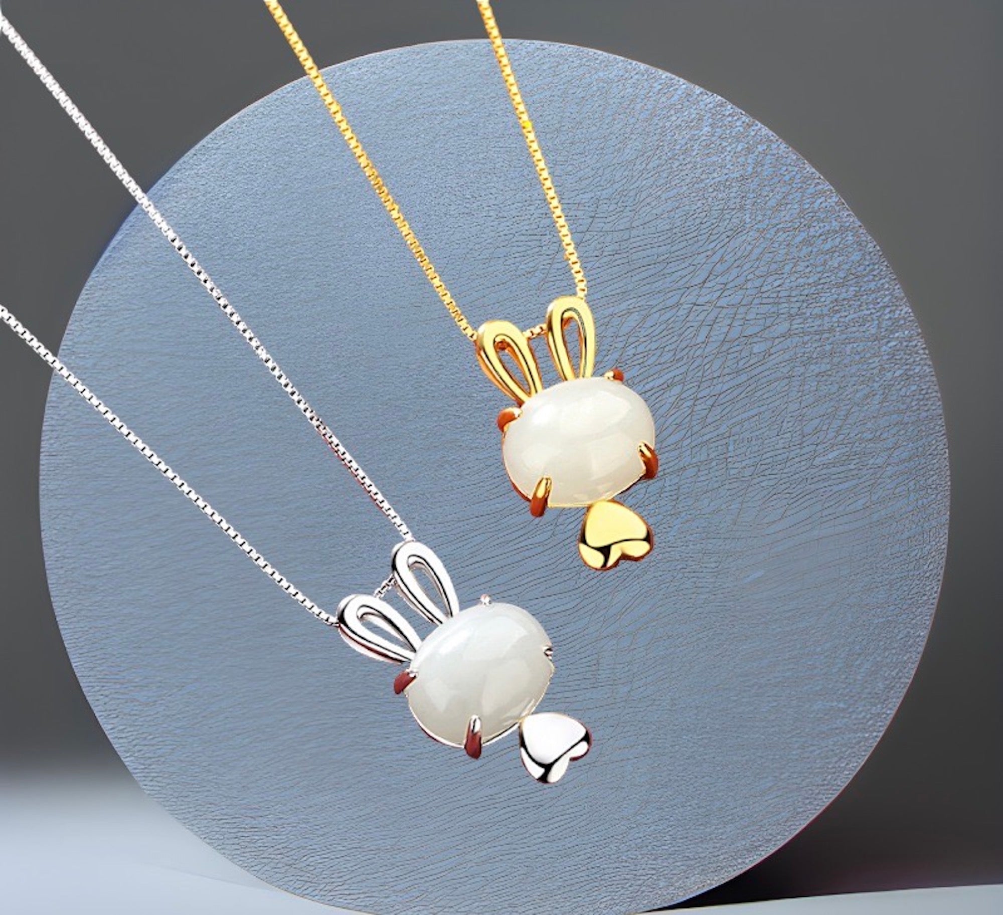 Two pendant necklaces with one featuring a gold-colored rabbit pendant and the other with a white pendant. Both pendants are attached to silver chains.