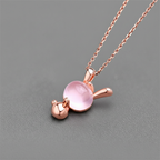 Rose gold necklace with a pink pendant on a gray background