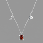 Silver necklace with a red gemstone pendant on a gray background
