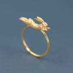 A gold-plated adjustable ring with a flying jade rabbit design on a blue background.