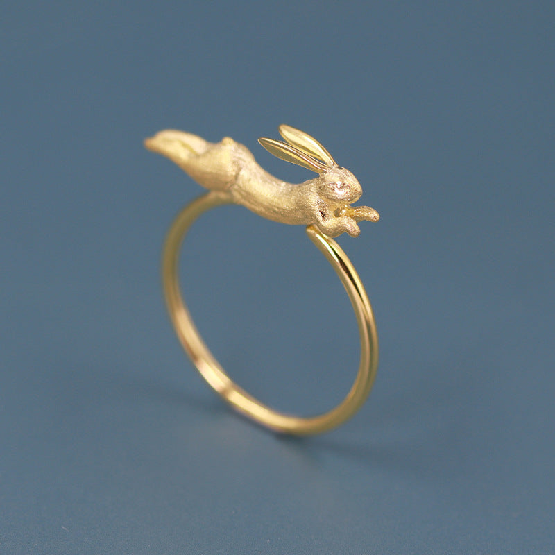 A gold-plated adjustable ring with a flying jade rabbit design on a blue background.