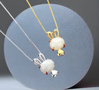 Two pendant necklaces with one featuring a gold-colored rabbit pendant and the other with a white pendant. Both pendants are attached to silver chains.